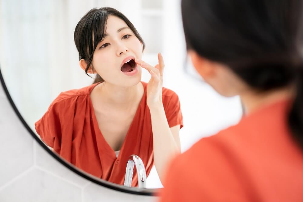 鏡で歯を見る女性